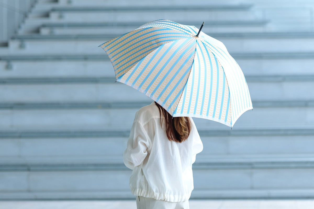 ストライプ柄の晴雨兼用傘を差している女性