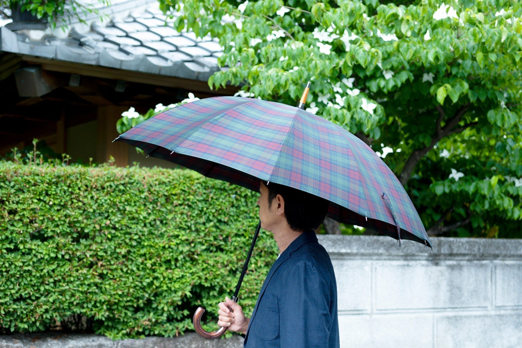 チェック柄の晴雨兼用傘を差している男性