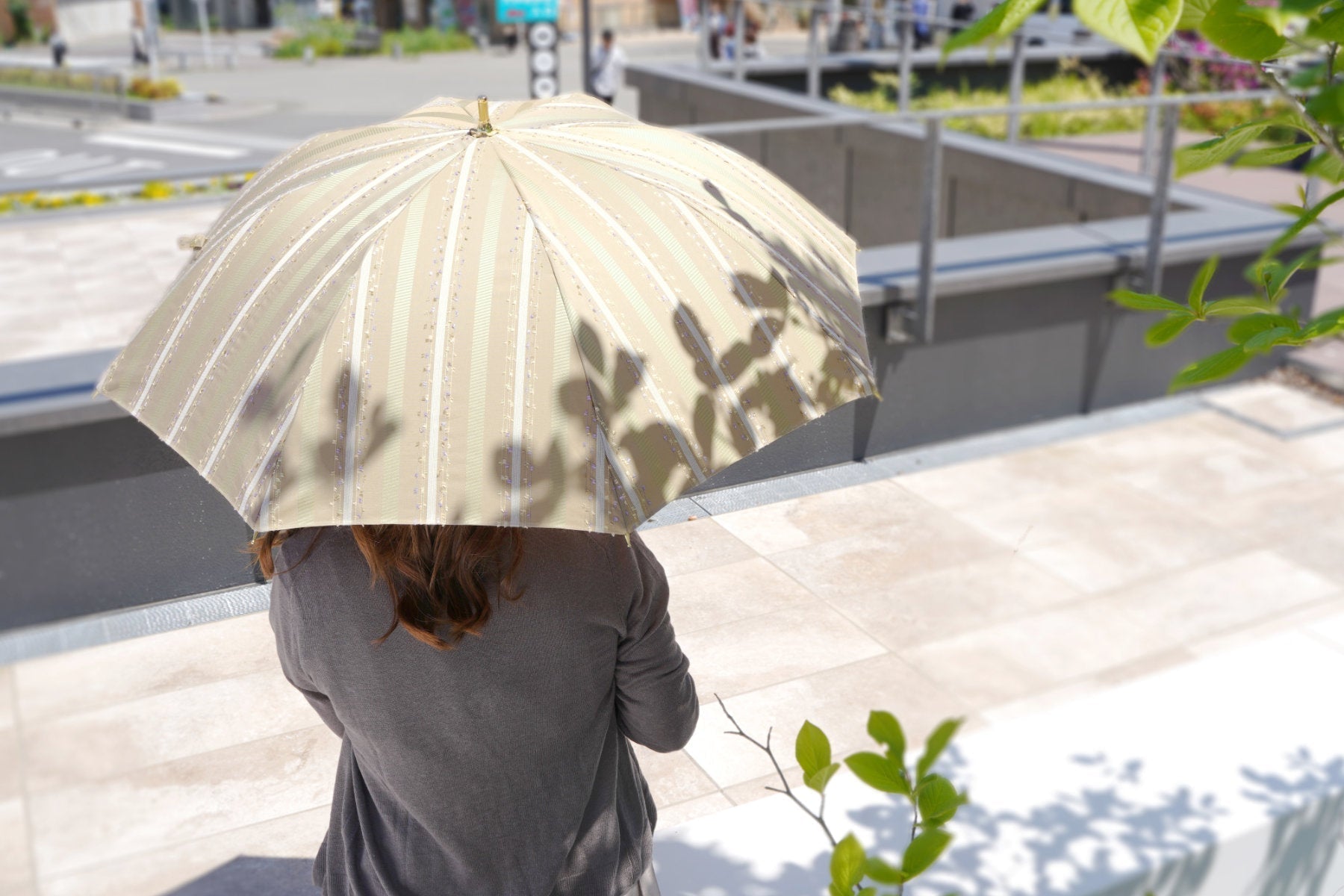 ストライプ柄の晴雨兼用日傘を差す女性
