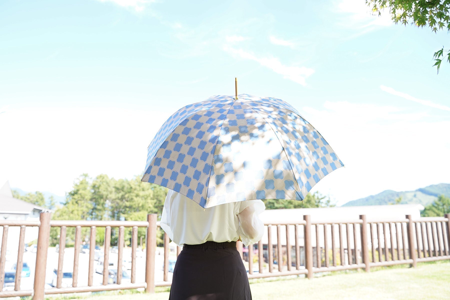 ブルーのドット柄の傘を差す女性