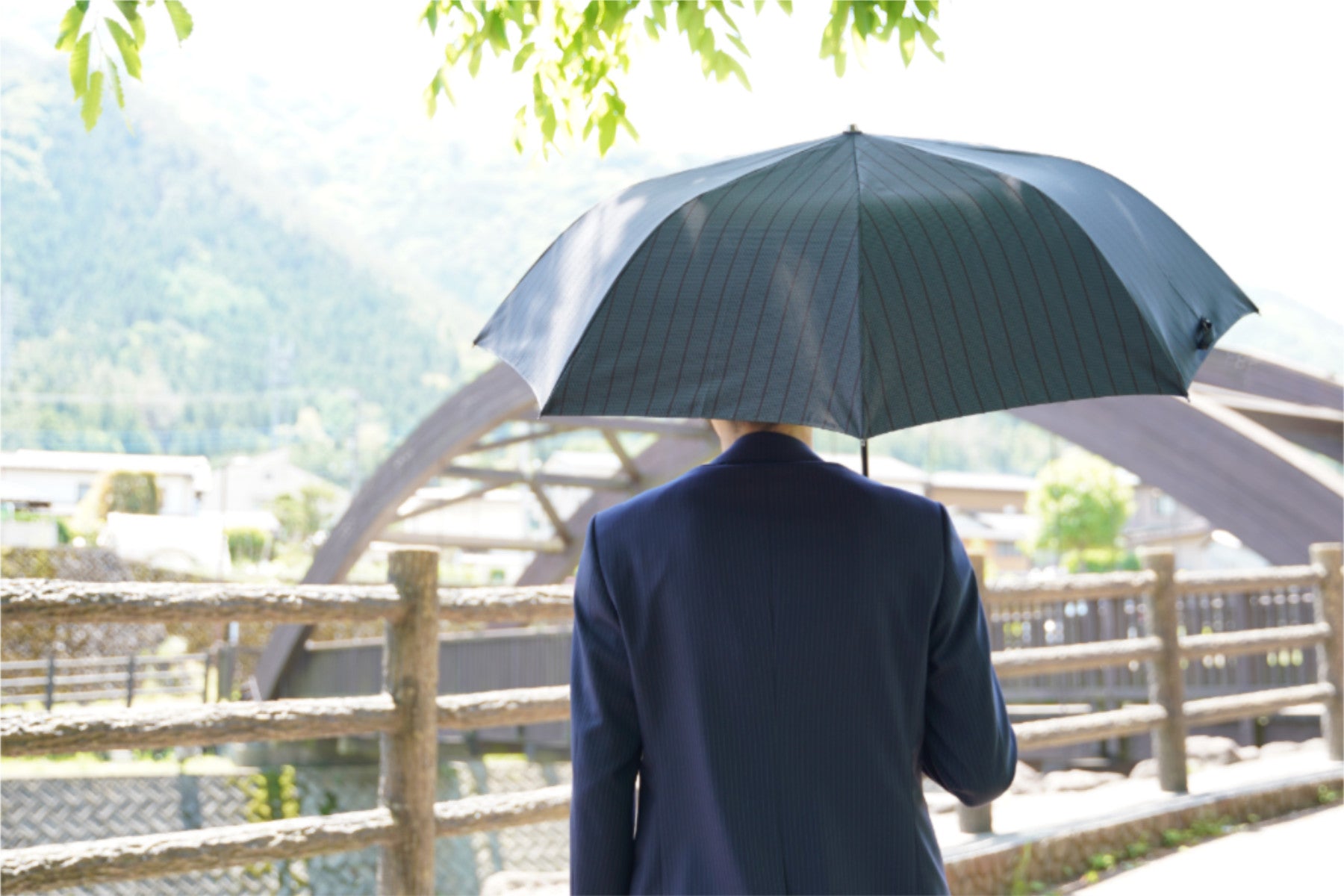 ストライプ柄のメンズ日傘を差す男性