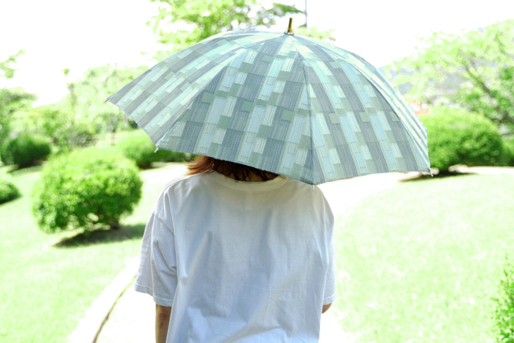 薄グリーンの晴雨兼用日傘を差す女性