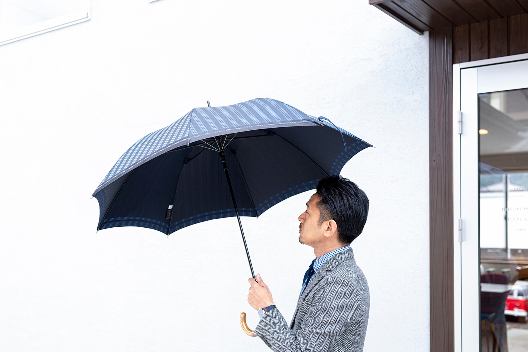 ストライプ柄のメンズ傘を差す男性