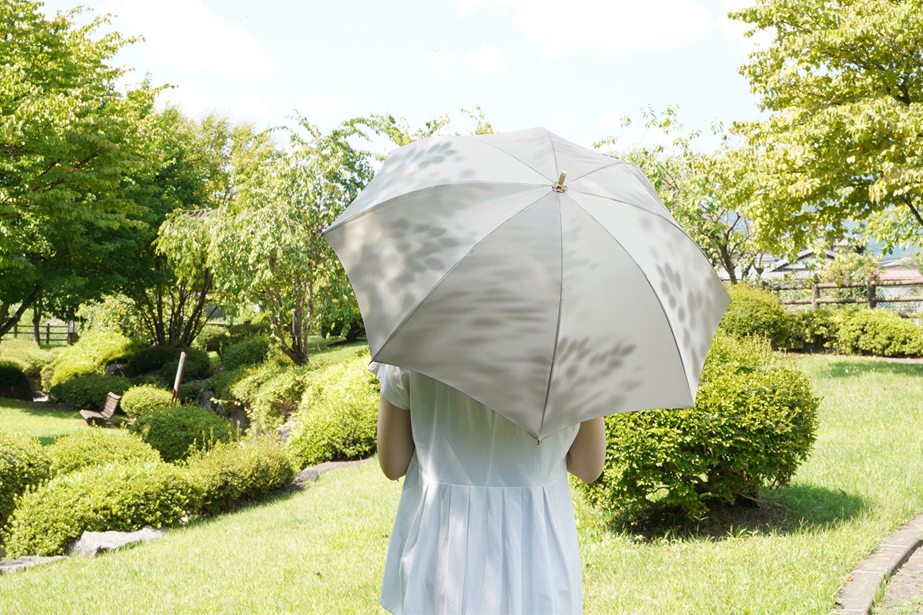 木漏れ日を表現した晴雨兼用日傘を差す女性
