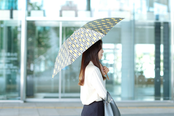 カーキ色の折りたたみ傘を差す女性