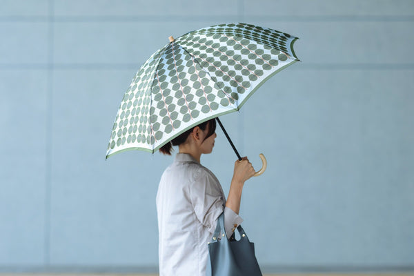 ベルサ柄の折りたたみ傘を持つ女性