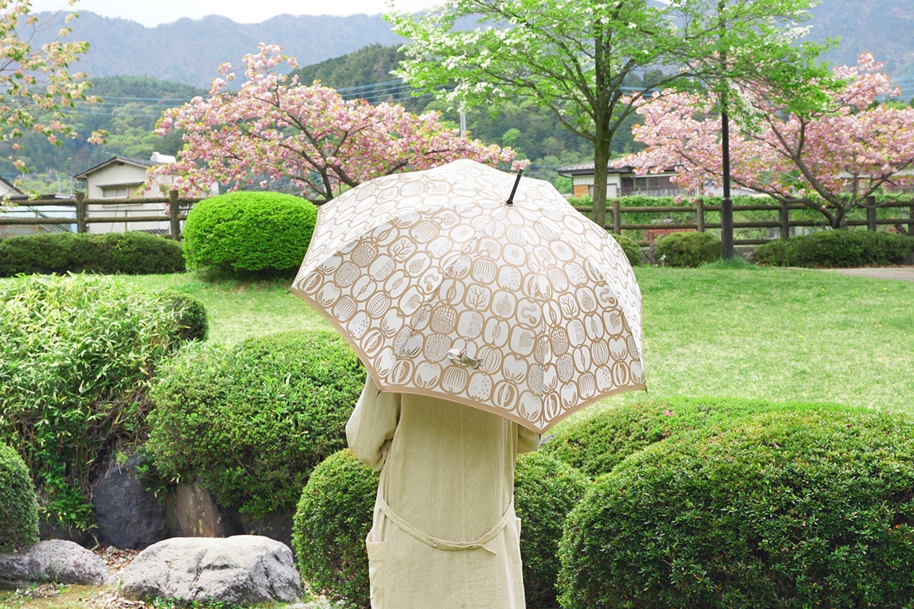 自然豊かな公園の中でフルーツ柄のレディース傘を差す女性