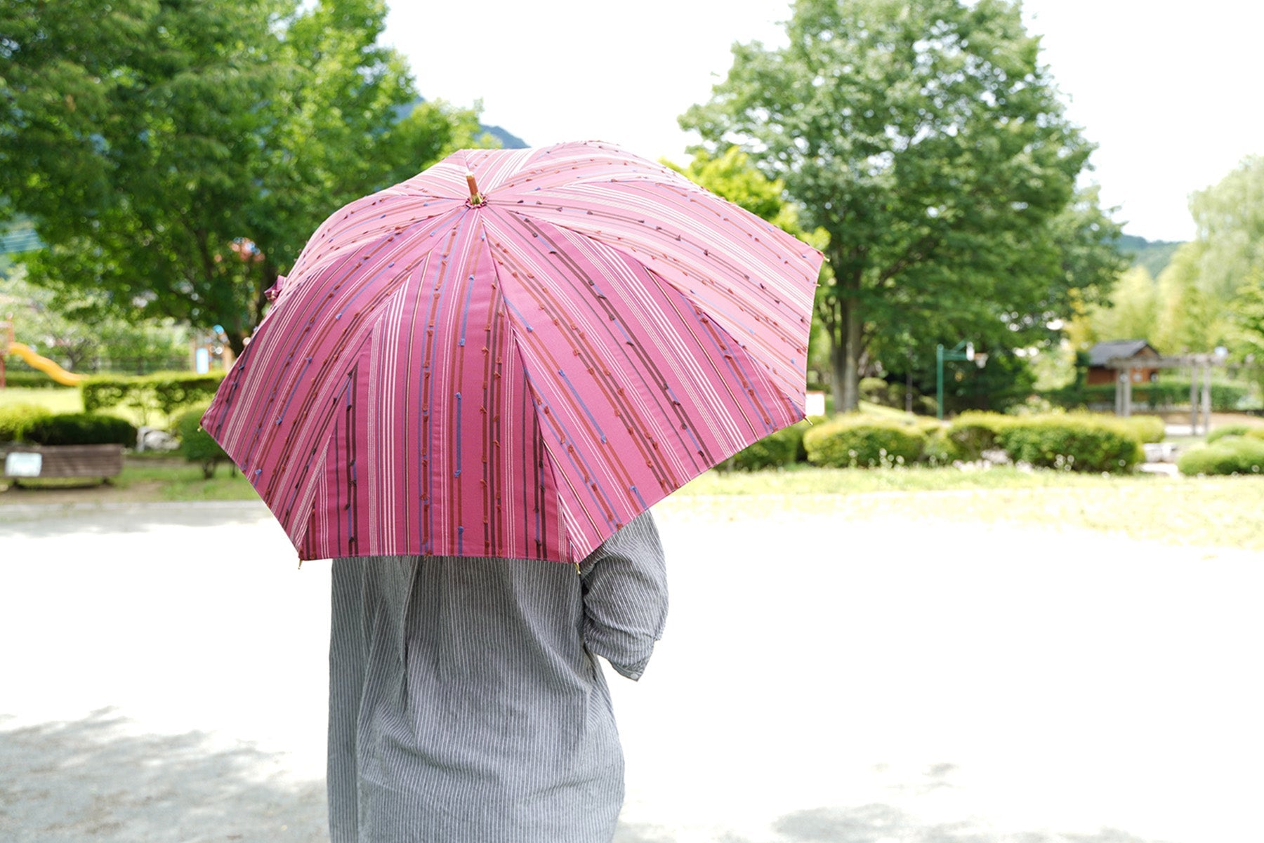 ピンク色の晴雨兼用日傘を差す女性
