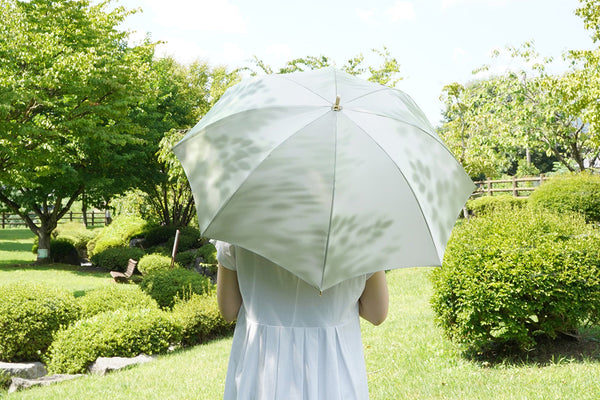 ブナ柄のグリーン色の晴雨兼用日傘を差す女性