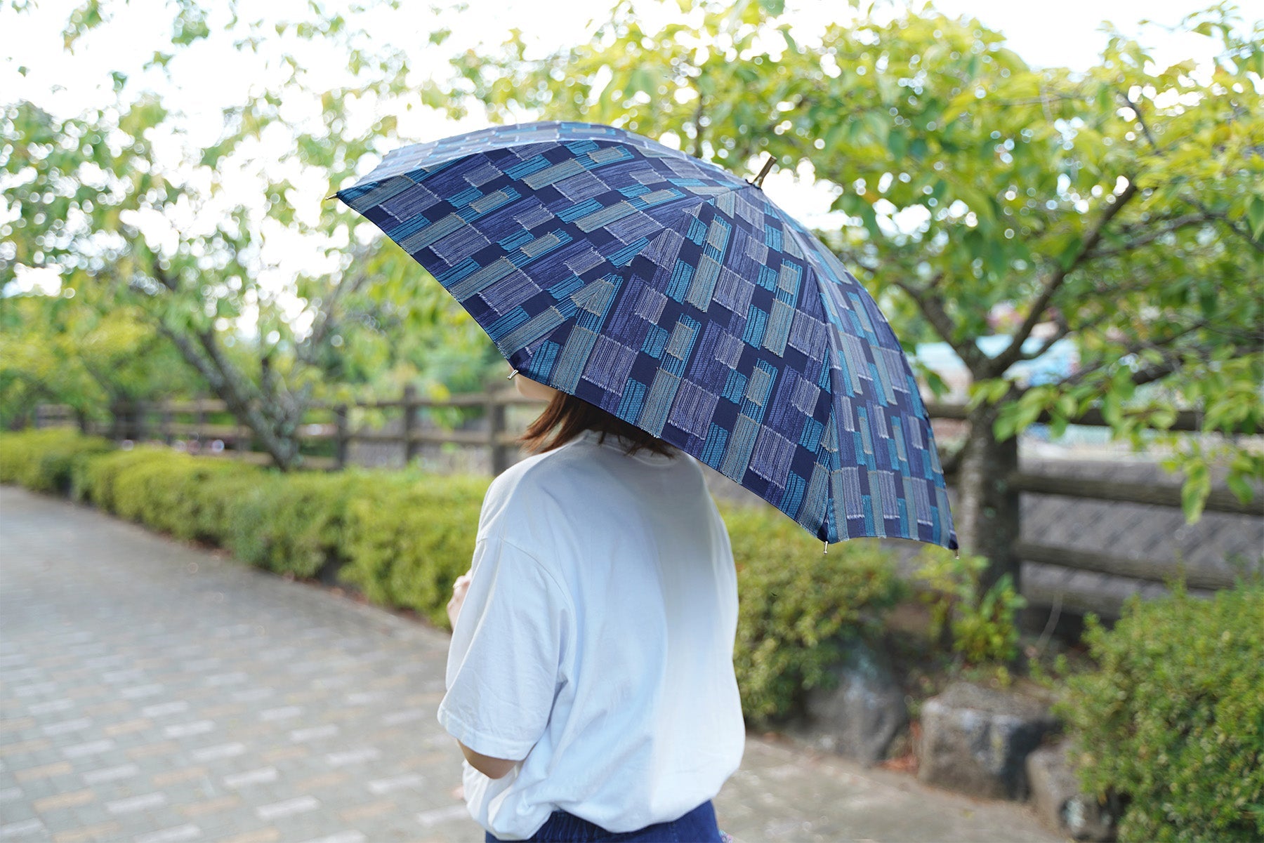 ダークブルー色の晴雨兼用日傘を差す女性
