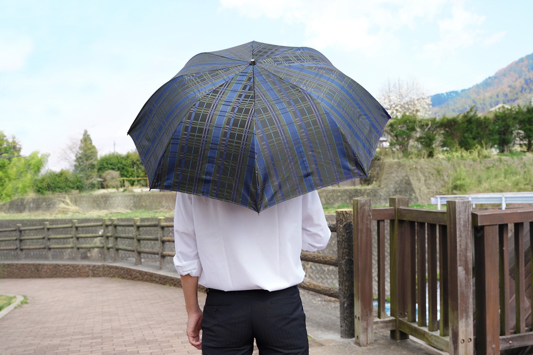 チェック柄のメンズ日傘を差す男性