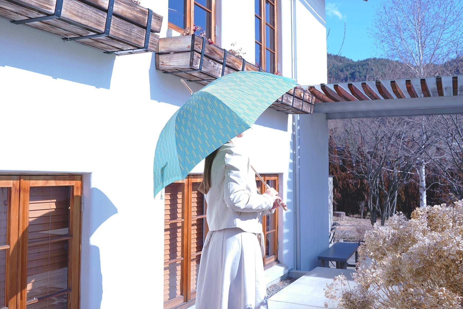 グリーンの晴雨兼用婦人長傘を差す女性