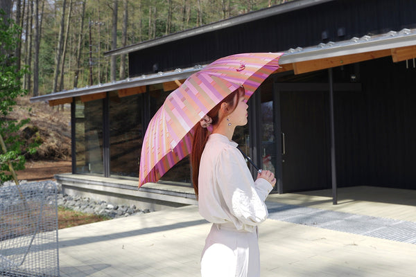 ピンク色の晴雨兼用レディース傘を差す女性