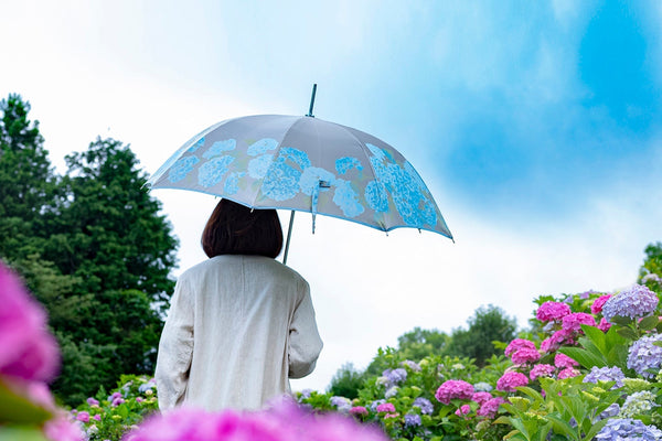 紫陽花畑の中で紫陽花柄の傘を差す女性
