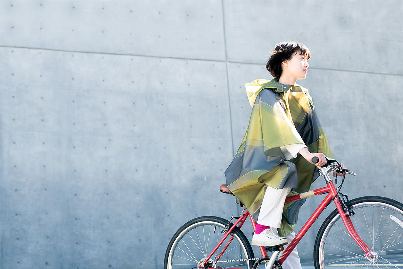 ポンチョを着て自転車にまたがる女性