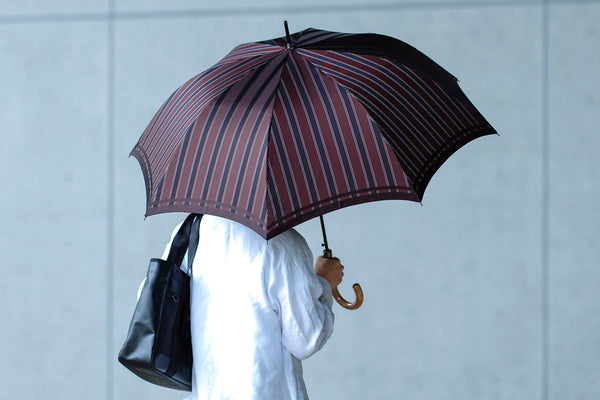 ストライプ柄のメンズ雨傘を指す男性