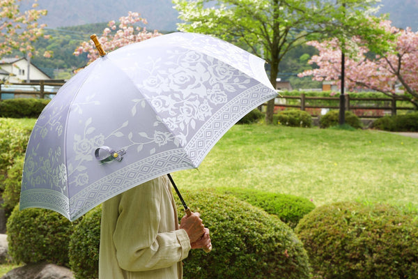 薄紫色のバラ柄の傘を差す女性