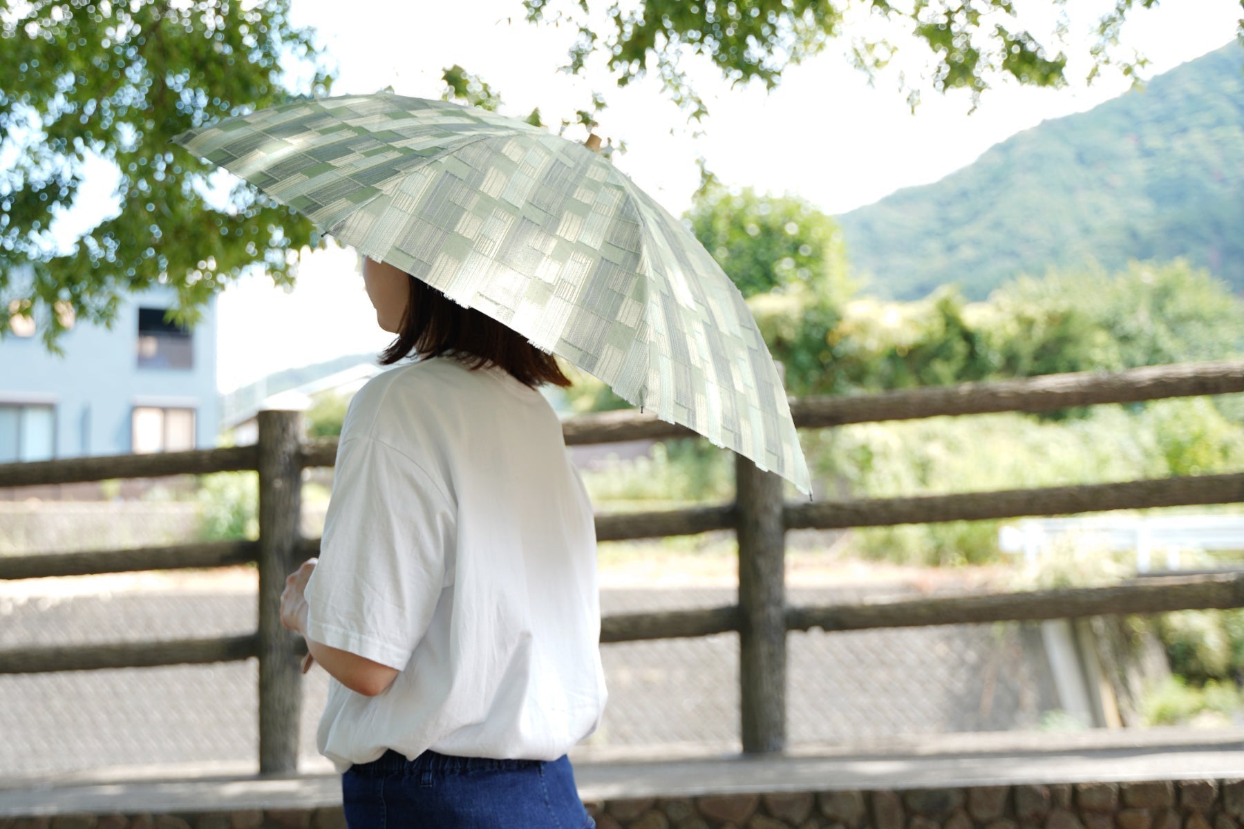 オリーブ色の晴雨兼用日傘を差す女性
