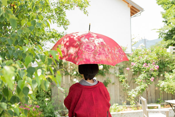 薔薇柄の赤い傘を差す着物姿の女性