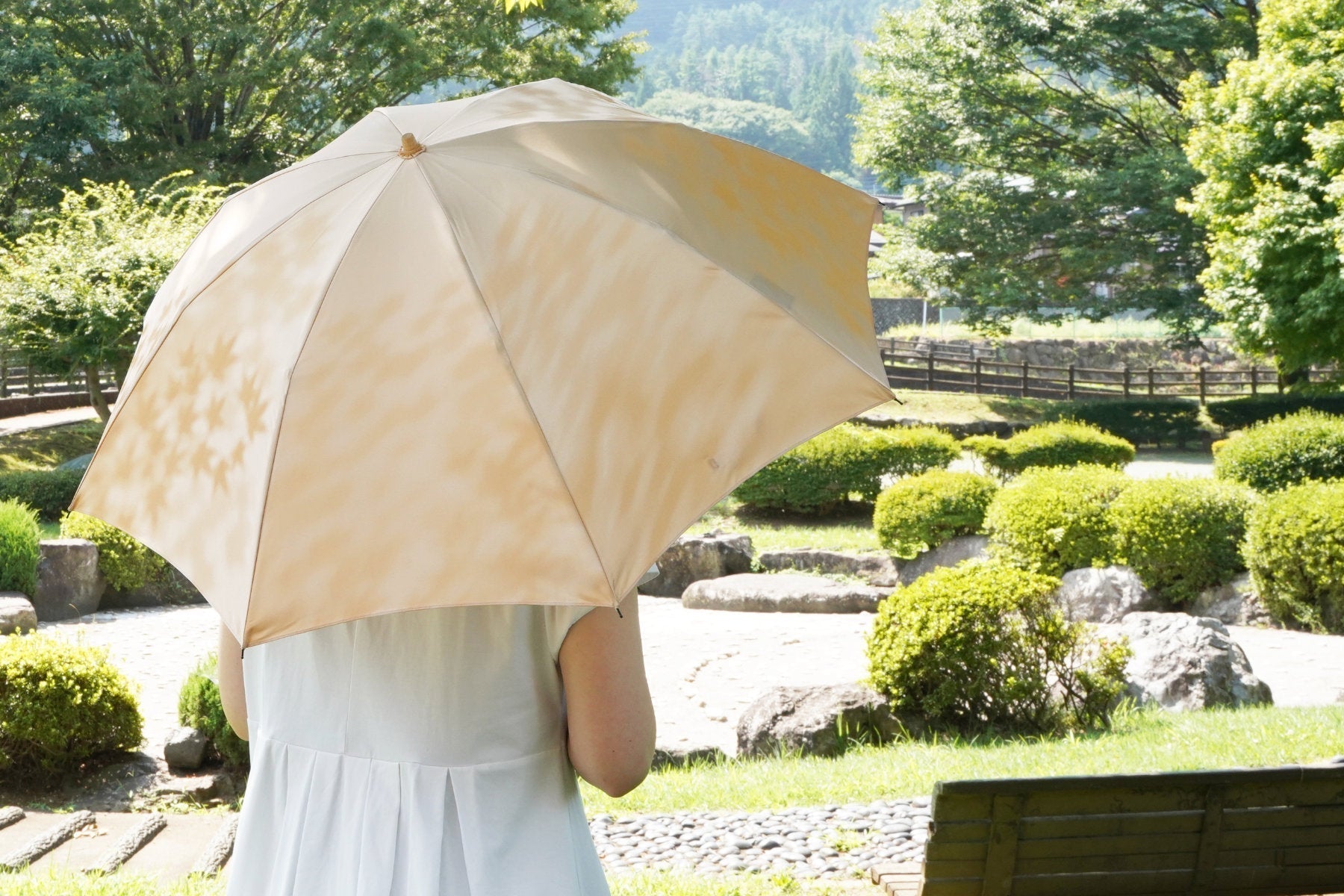 黄色の木漏れ日柄の日傘を差す女性
