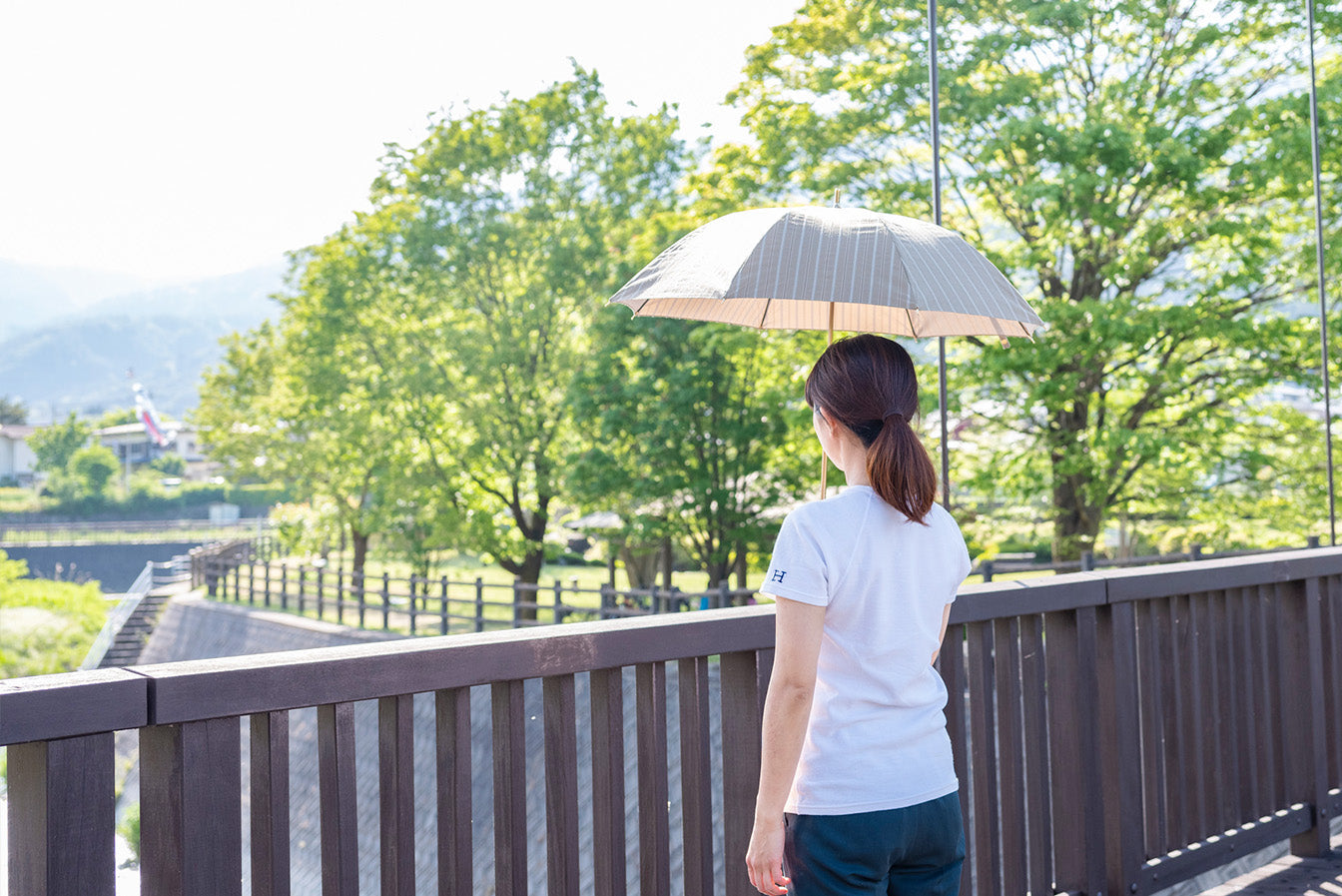 カーキ色の晴雨兼用日傘を差す女性