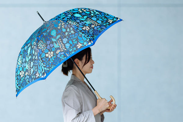 ブルーのハーバリウム柄の晴雨兼用傘を差す女性