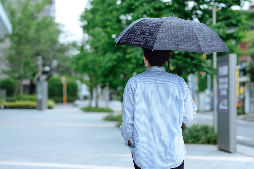 黒色の千鳥柄の折りたたみ傘を差す男性