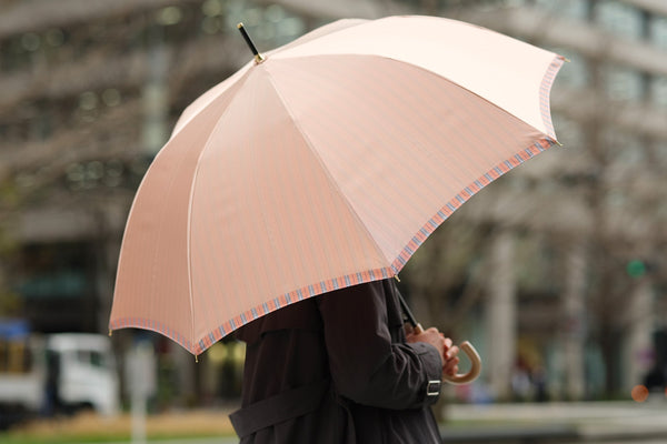 ピンクオレンジ色の傘を差す女性