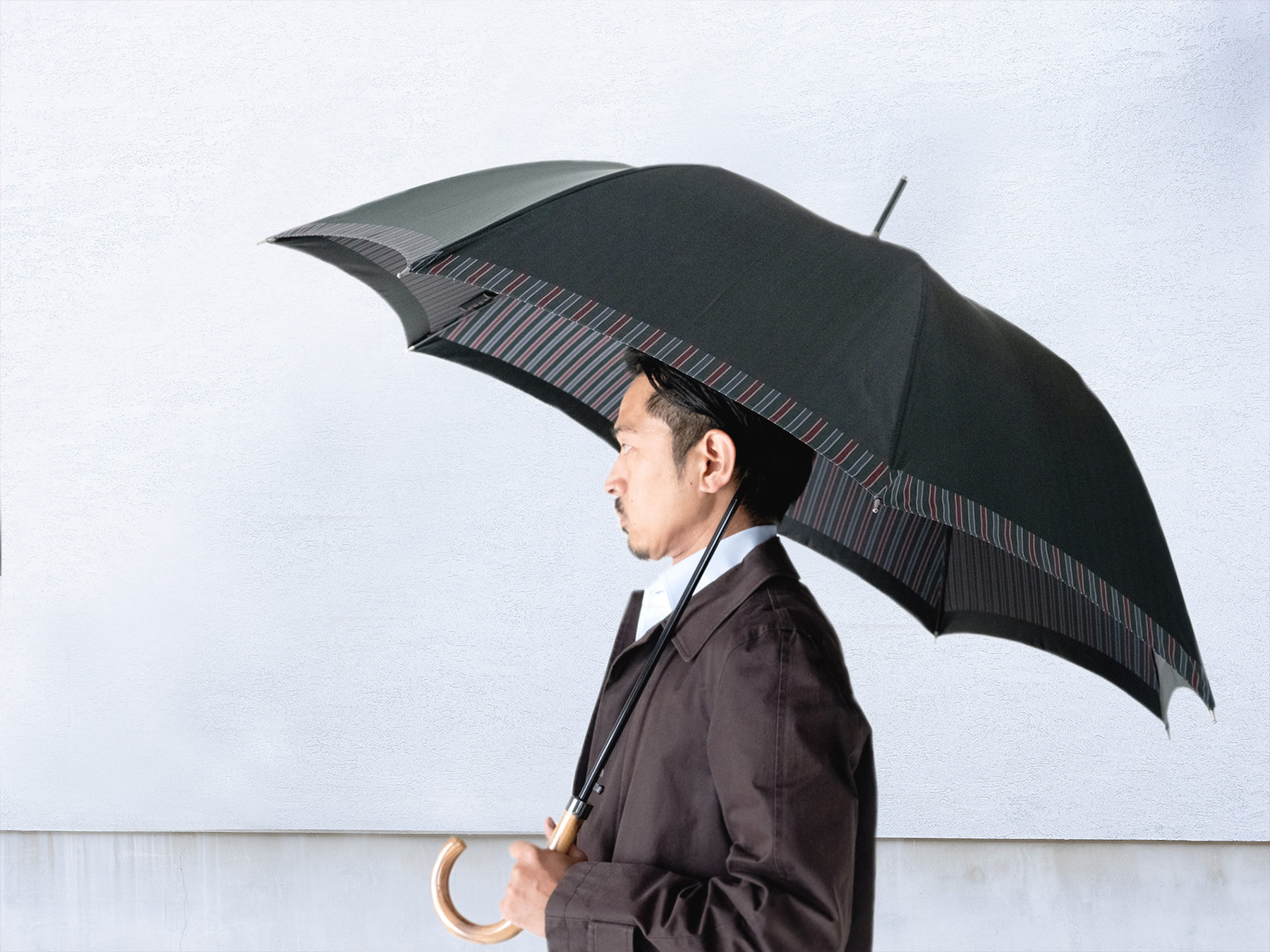 内ストライプ柄のメンズ傘を差す男性