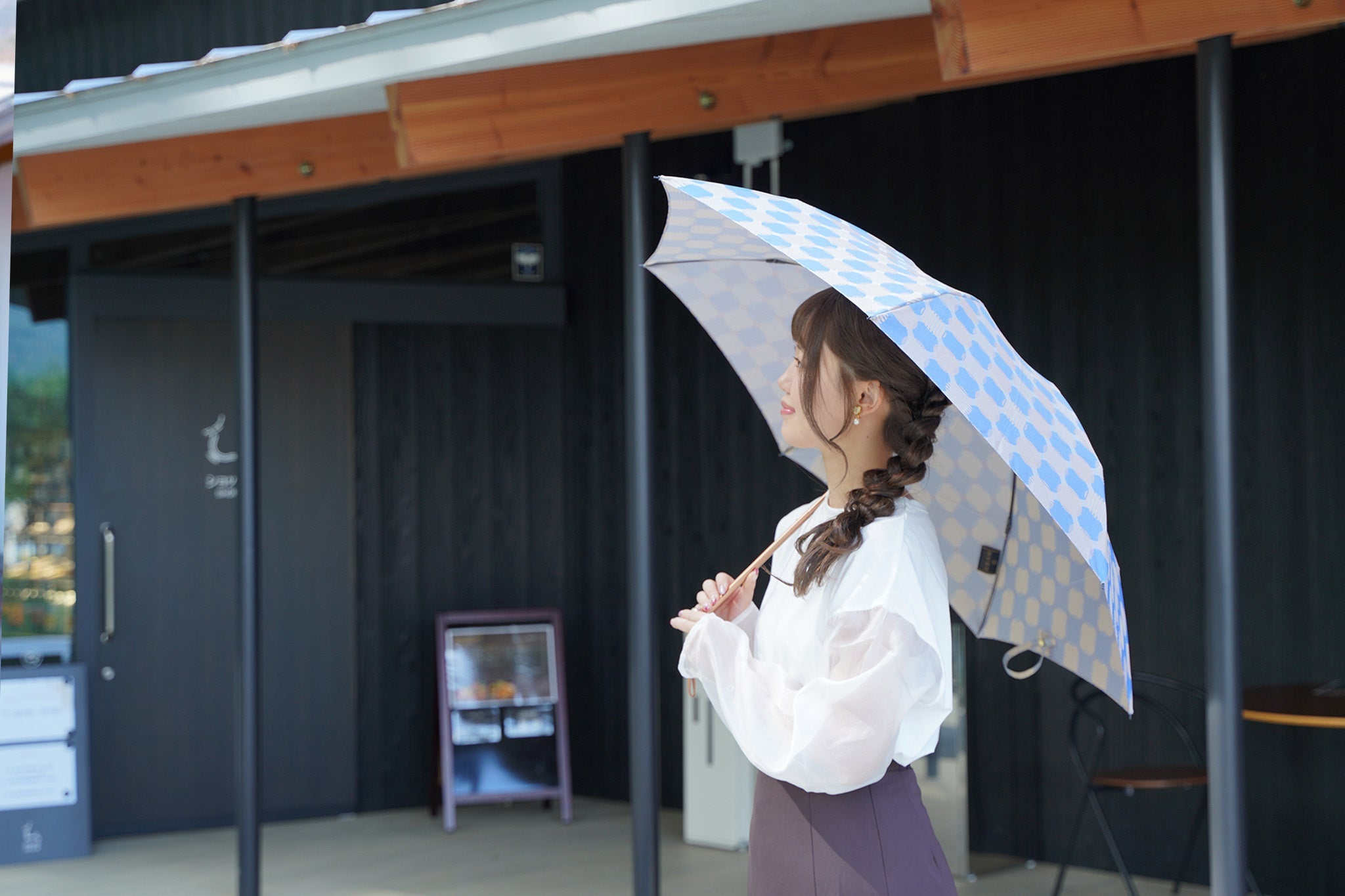 ブルーの折りたたみ傘を差す女性