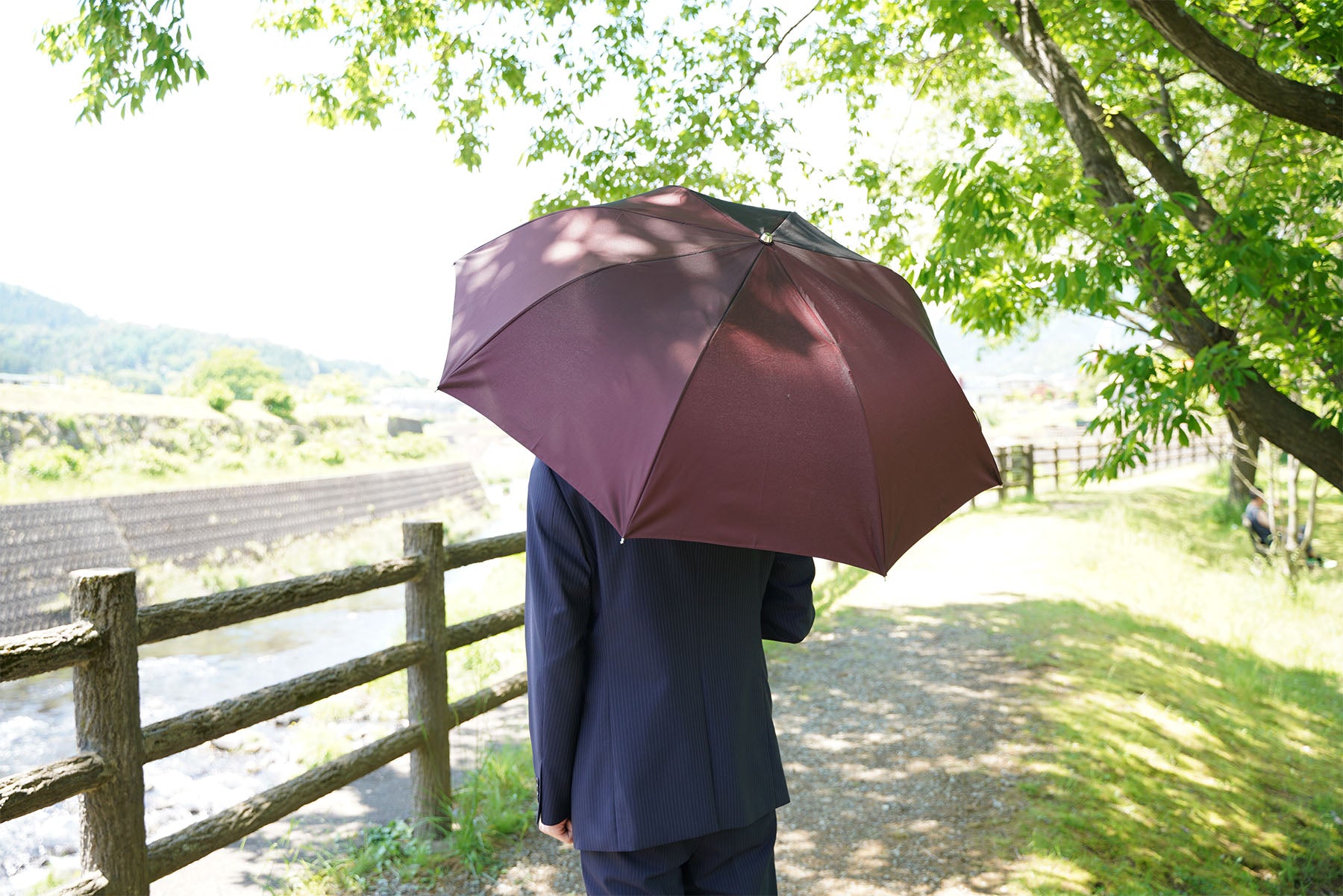 ワイン色のメンズ折りたたみ傘を差す男性