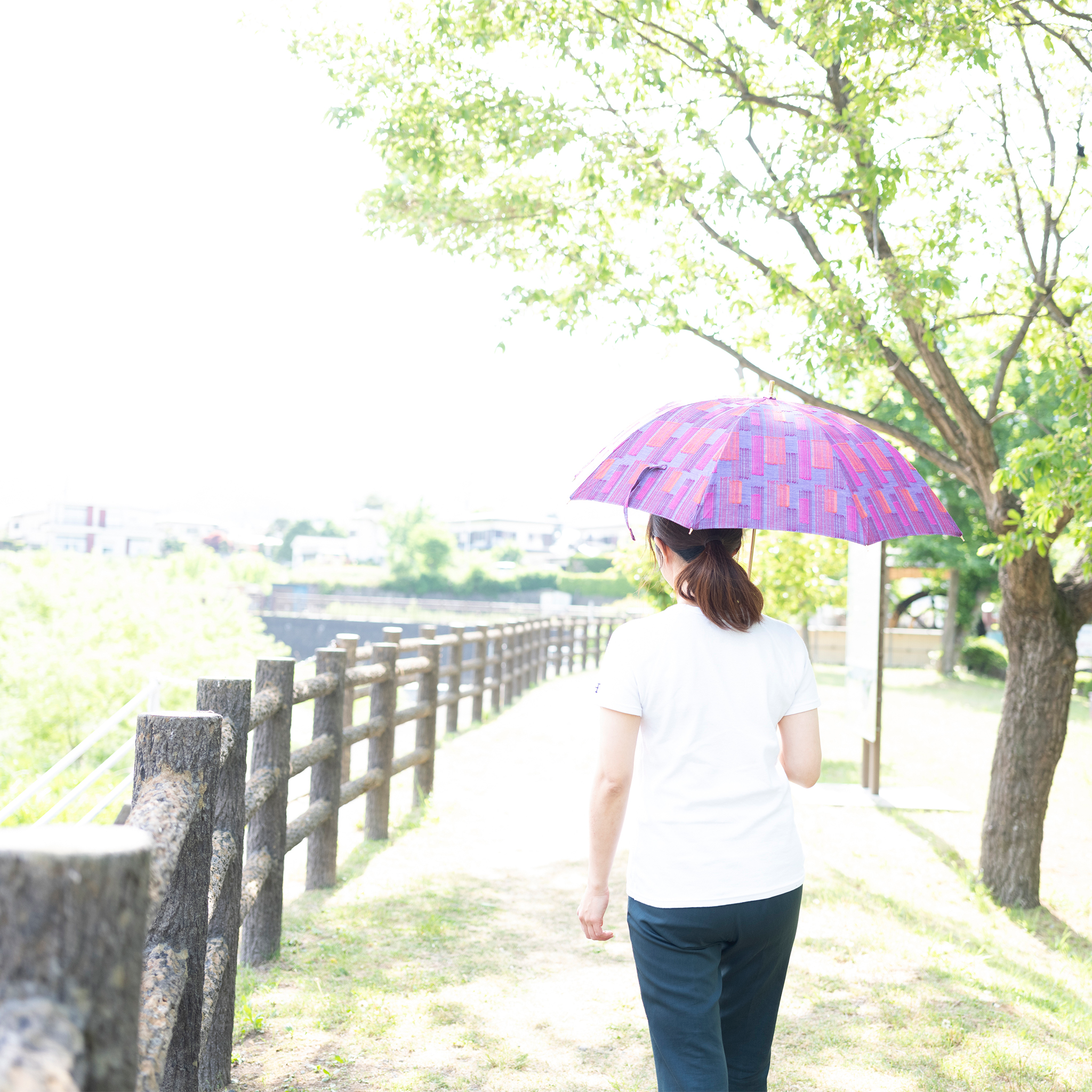 紫色の晴雨兼用日傘を差す女性